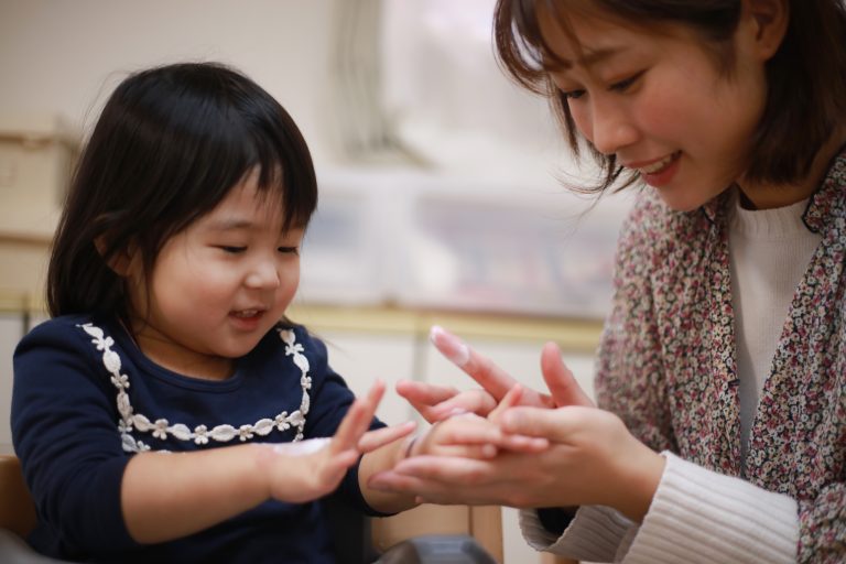 女の子に保湿クリームを塗る母親